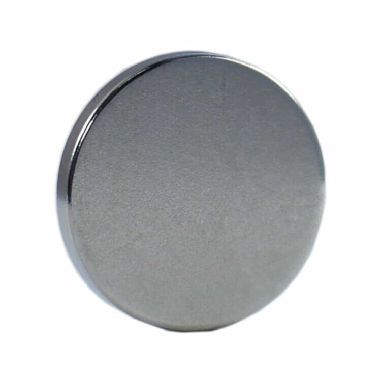 Dynamag er et slankt, cylindrisk værktøj med en mat, grå metaloverflade. Det har en fin, struktureret tekstur og en afrundet top. På siden er der en række små, præcise riller, der giver et godt greb. Den nederste del har en tydelig, skinnende kant. Ingen synlige knapper eller symboler er til stede, hvilket giver et minimalistisk udtryk.