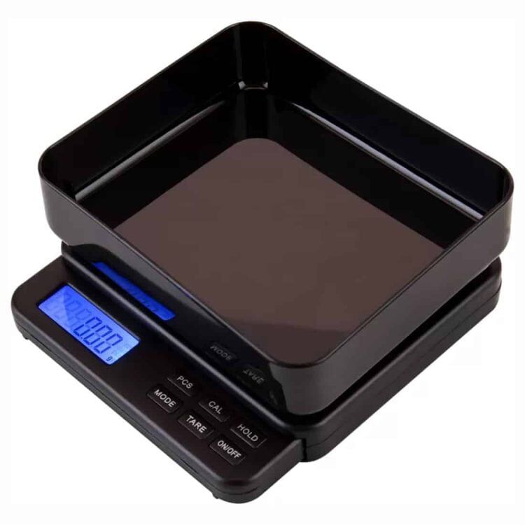 En digital vægt præsenteres med en glat, sort plastikoverflade og en stor, tydelig LCD-skærm. Vægten har en kapacitet på 1000 gram, og en vægtplade i rustfrit stål, der har en let børstet finish. Under skærmen findes to knapper, som er placeret centralt, og der er en let skrå kant, der giver en moderne æstetik.