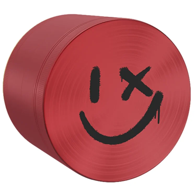 En rund, lyserød smiley med en glad ansigtsudtryk pryder overfladen. Øjnene er små, sorte cirkler, mens munden er en bue, der stråler af glæde. Materialet ser glat og skinnende ud, hvilket skaber en let refleksion. Kanten er tydeligt afgrænset, og den samlede form er perfekt cirkulær med en diameter på 63 mm.