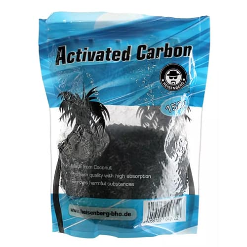 En transparent beholder med en sort, granuleret aktivkul, der har en let glinsende overflade. Beholderens låg er hvidt og skrueformat, hvilket sikrer tæt lukning. Etiket med tydelig sort tekst pryder fronten og indeholder information om produktet. Beholderens form er cylindrisk, og den står på en ensfarvet overflade, der fremhæver den sorte kulfarve.