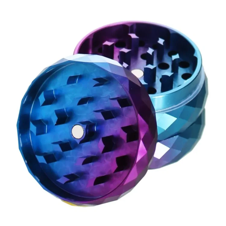 En diamantformet kværn med en diameter på 50 mm præsenterer sig i en skinnende, metallisk sølvfarve. Overfladen har et mønster af små, skarpe kanter, der skaber en tekstureret effekt. Kværnen består af flere sektioner, herunder et låg med en let buet form og en praktisk skruemekanisme. Indersiden viser skarpe tænder til effektiv kværning.