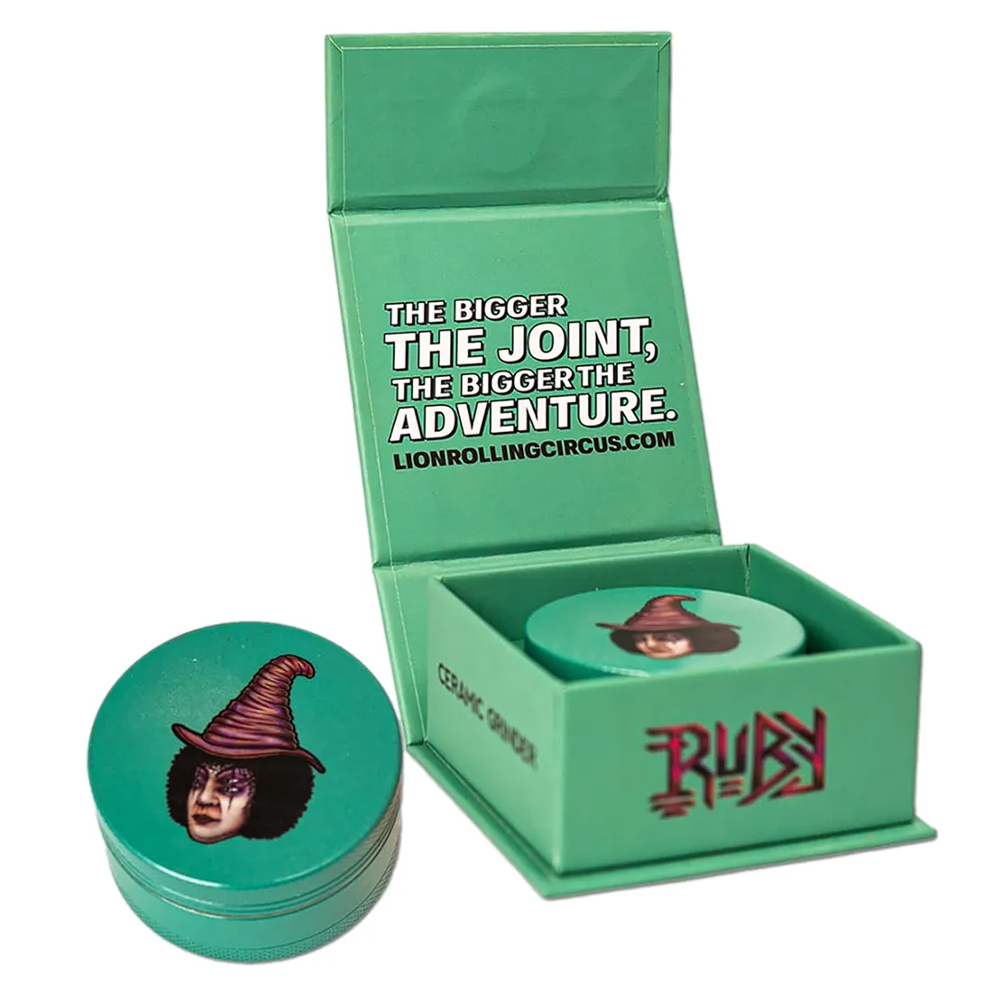 En keramisk kværn med en dyb ruby-rød farve og en glat, blank overflade. Kværnen har en rund form med en diameter på 50 mm og er udstyret med en sølvfarvet metalhåndtag. Det øverste låg har et indgraveret mønster, mens bunden er mere enkel. Kværnens samlede design udstråler elegance og funktionalitet.