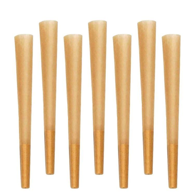 Syv løs brune kegler er samlet i en bunke, hver kegle har en glat overflade og en konisk form. Farven varierer fra lys til mørk brun, med en let glans, der fremhæver teksturen. Keglerne står på en lys overflade, og de er forskudt i højden, hvilket skaber en dynamisk komposition. Der er ingen synlige mærker eller tekst.