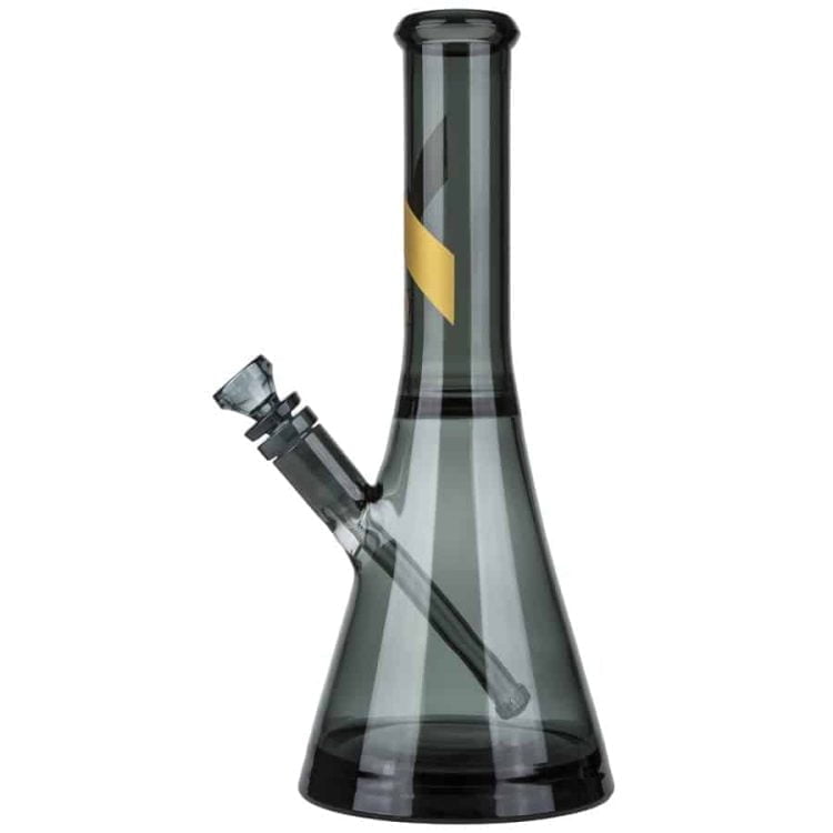 En 31 cm høj bong i klart, naturligt røget glas præsenterer sig med en elegant, slank form. Den runde bund giver stabilitet, mens den udvidede hals muliggør en behagelig indånding. Der er en enkelt, diskret skål placeret på siden, og overfladen har en glat tekstur, der fremhæver glasets gennemsigtighed og reflekterende egenskaber.