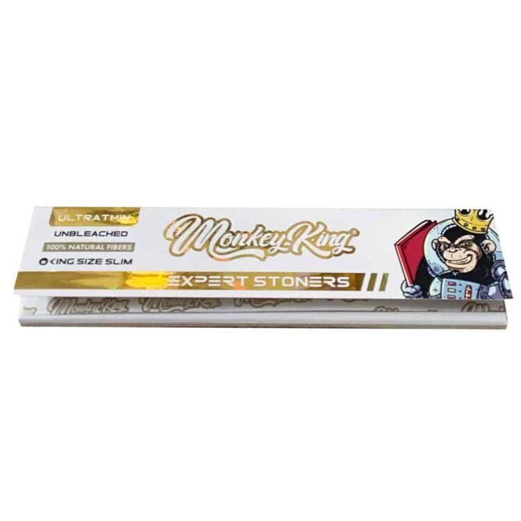 En pakke Monkey King - Expert Stoners rullepapir, med en kronet abe med solbriller og en rød bog, der promoverer "Ultra Thin", "Unbleached" og "100% Natural Fibers" i King Size Slim.