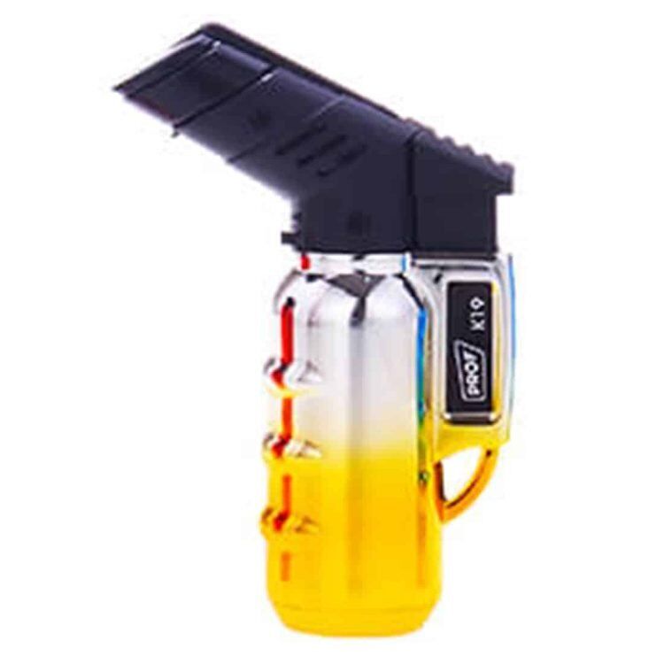 En mini gasbrænder præsenterer sig med en sølvfarvet metaloverflade, der reflekterer lys. Den har en kompakt, cylindrisk form med en flammejustering og en sikkerhedsknap. Øverst er der en sort, ergonomisk håndtag med ridser for bedre greb. Flammen er blå og intens, hvilket indikerer en høj temperatur. Designet er minimalistisk og funktionelt.