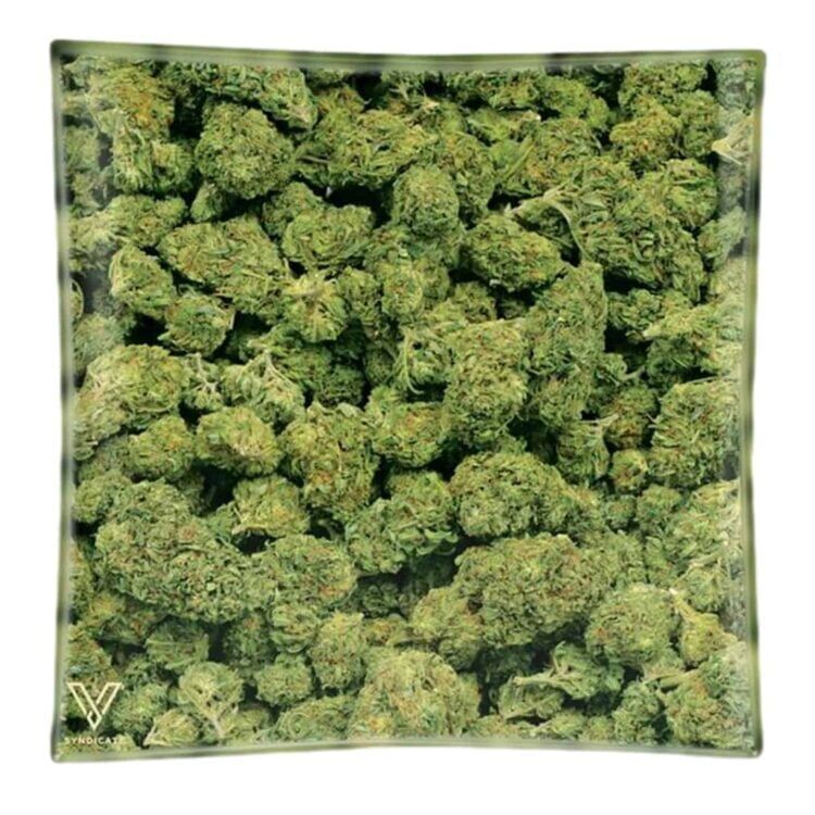 Et askebæger i klart glas med en rund, lav profil. Det har en glat overflade og en let buet kant, der giver en elegant form. I midten er der en indgravering, der skaber et subtilt mønster. Askebægeret har fire små forhøjninger til placering af cigaretter, hvilket tilføjer funktionalitet til det enkle design. Farven er gennemsigtig, og glasset skinner ved lys.