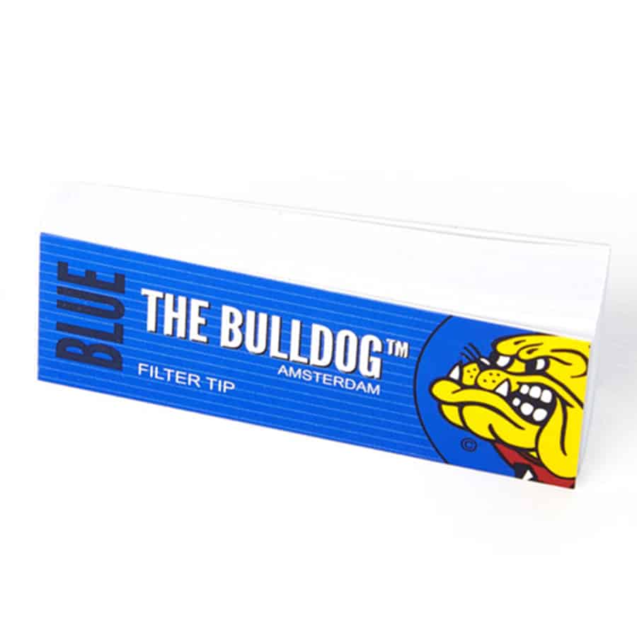Blå filtertips prydet med en subtil, hvid skrift, der angiver mærket "The Bulldog Amsterdam". Tipsene har en glat overflade og en let gennemsigtig struktur, der fremhæver den blå farve. De er placeret i en cirkulær form, hvilket giver en kompakt og organiseret fremtoning. Omkring tipsene ses en naturlig baggrund, der tilføjer dybde til kompositionen.