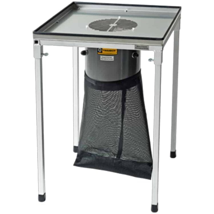 En arbejdsstation med en rektangulær form, fremstillet af metal og plast. Overfladen er dækket af en grå tekstur, og der er synlige knapper i sort. En arbejdsflade er placeret centralt, omgivet af flere opbevaringsrum med lukkede låger. En ledning er synlig i bunden, og der er små hjul, hvilket muliggør mobilitet.