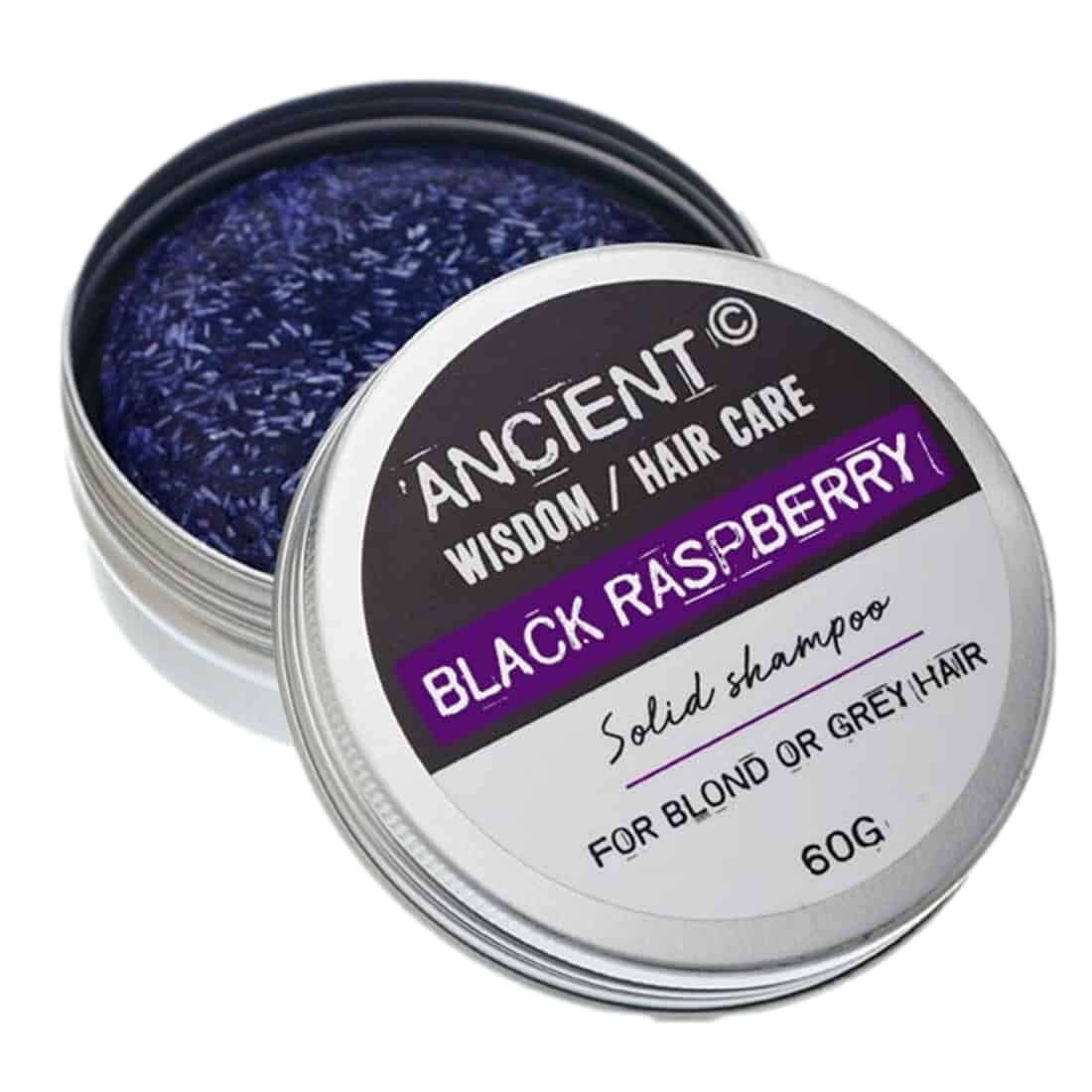 En solid shampoo med en mørk, næsten sort farve præsenterer sig i en rund form. Overfladen er glat med en let glinsende finish. Der er en tekstur, som indikerer en kompakt struktur. På emballagen ses små, tydelige skrifttyper med produktinformation i hvid farve, placeret centralt. Baggrunden er neutral, hvilket fremhæver produktet.