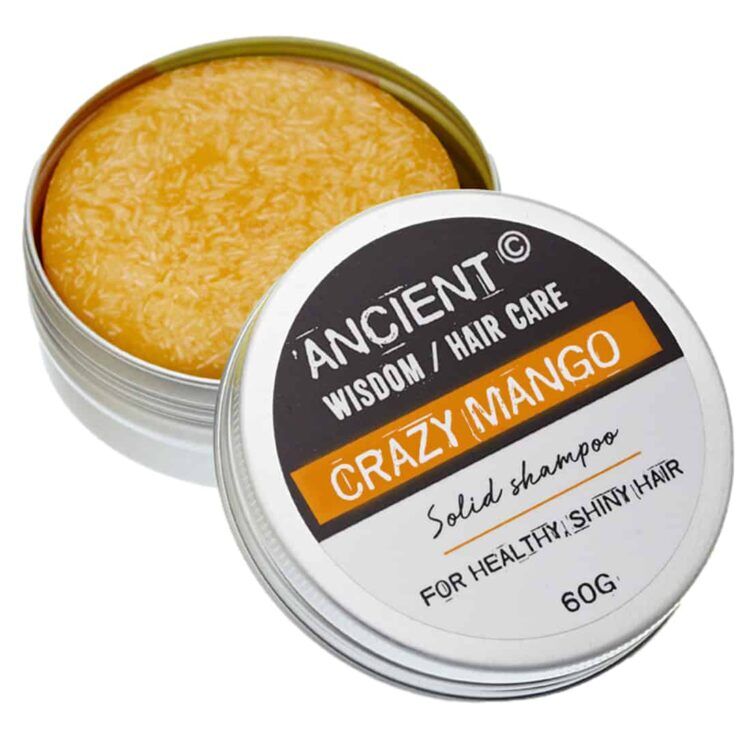 En rund, flad shampoo-bar præsenterer sig i en dyb, gylden-orange farve med let glinsende overflade. Den har en glat tekstur med små, fine luftbobler, der skaber et uregelmæssigt mønster. Kanten er let buet, og midten bærer en indgraveret tekst med produktinformation. Vægten er 60 gram, og størrelsen er kompakt for nem opbevaring.