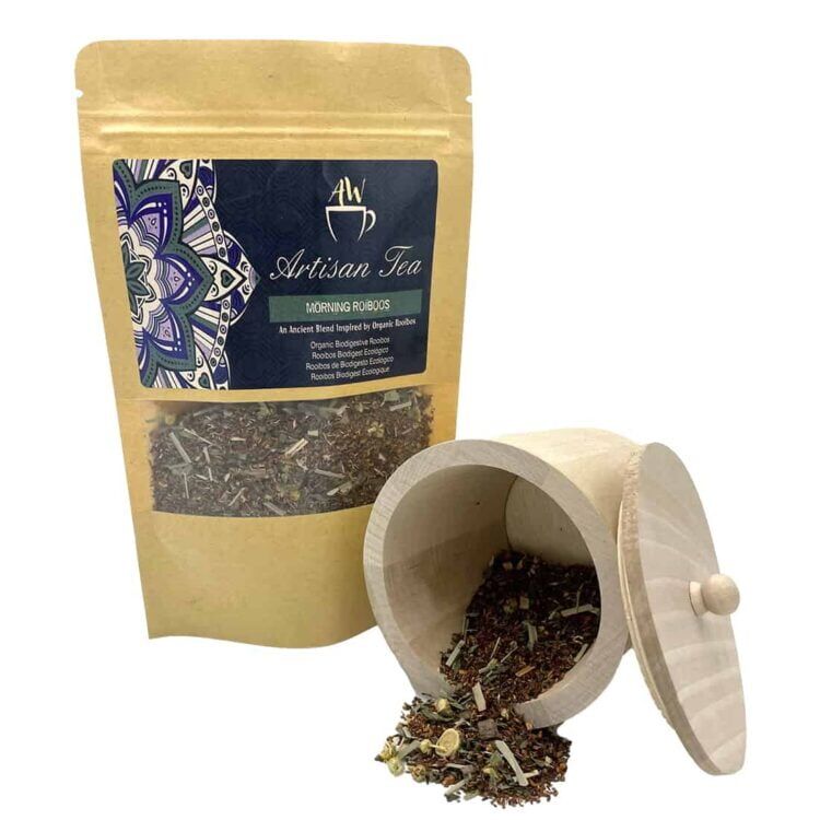 En dyb rødbrun te, der fremstår klar i en gennemsigtig tekrus. Overfladen er let boblet, hvilket indikerer varme. En lille skefuld teblade i sort og grøn farve ligger ved siden af kruset, på en lys træoverflade. Baggrunden er uklar, hvilket skaber fokus på tekruset og tebladene.