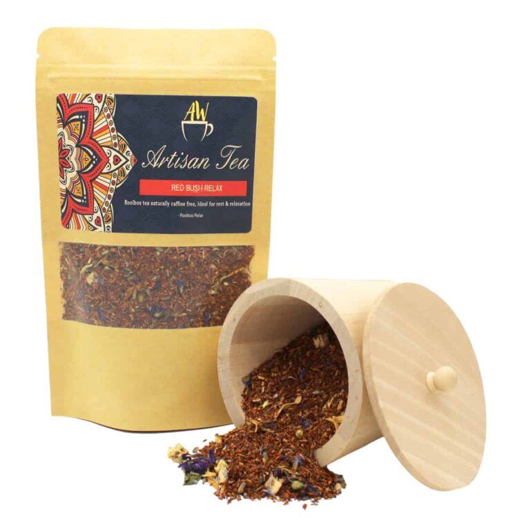 En transparent tebeholder med en fyldig, rødbrun væske, der har en glinsende overflade. Beholderen er rund med en smal åbning og en solid bund. I nærheden ses et par tørrede urter med grønne og brune nuancer, der tilføjer tekstur. Baggrunden er lys og neutral, hvilket fremhæver teens farve og de naturlige elementer.