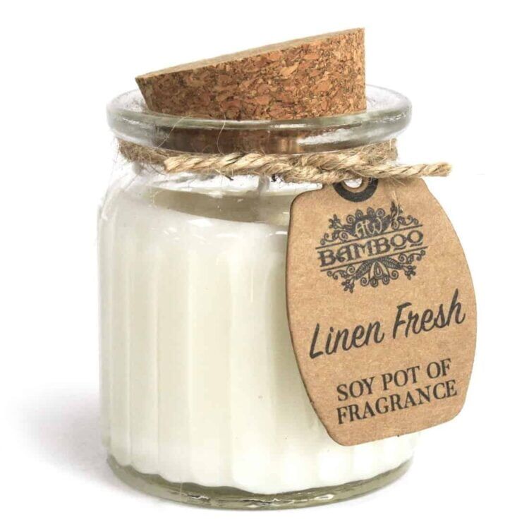 En cylindrisk beholder i bambus med en naturlig, lys træfarve. Beholderen har en glat overflade og er prydet med en hvid voksagtig inderside. Øverste kant er let buet, og der er en label i sort tekst, der angiver duften. Lysvoksen er hvid, og der er en svag glød fra flammen, der giver et varmt skær.