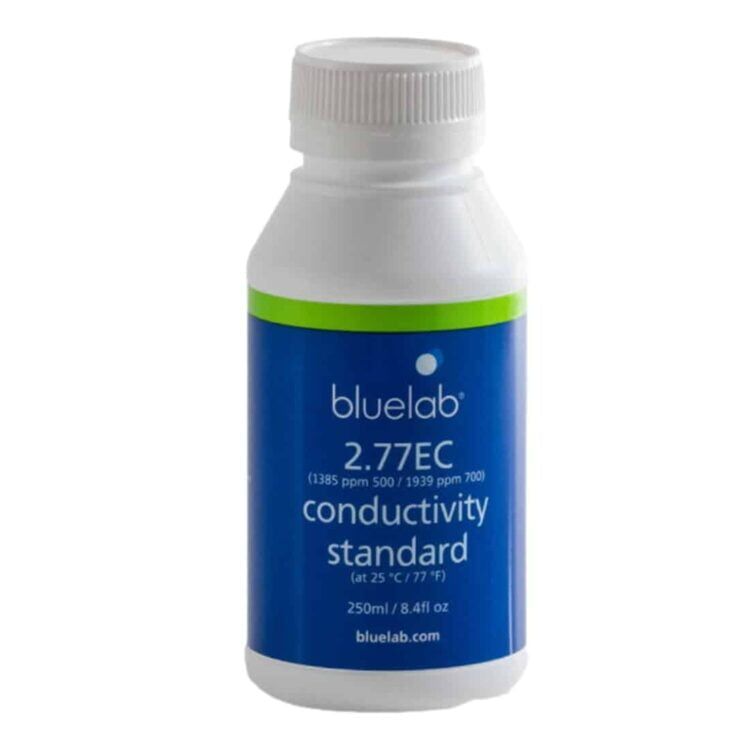 En gennemsigtig flaske med en blå væske indeni, der fylder det meste af flasken. Flaskens label er hvid med sort tekst og indeholder information om kalibreringsvæsken, herunder koncentration og volumen. Kappen er sort og har en lille åbning til dosering. Flasken står på en flad overflade med en neutral baggrund.