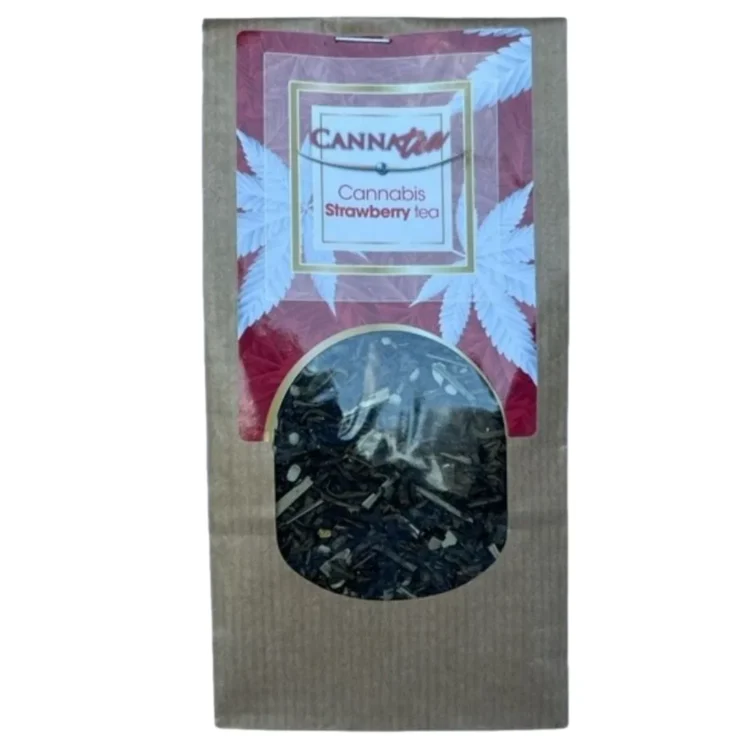 Canna Tea i jordbærvariant præsenteres i en transparent, genanvendelig pose med en gyldenbrun farve. Posens overflade har en mat tekstur, og der er et grønt logo øverst. Indholdet består af tørrede jordbærstykker, der har en rødlig nuance, og små, grønne urter. Posen har en lukning i toppen samt informationstekst i sort og hvid farve.