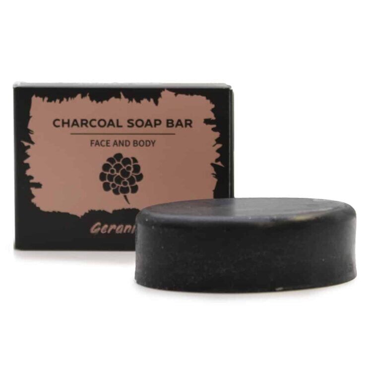 En mørkegrå sæbebar med en glat overflade og en let skinnende finish. Sæben har en firkantet form med afrundede hjørner. Der er indgraveret tekst på overfladen, som angiver produktets navn. Den har en subtil duft af geranium, og der ses små, fine strukturer, der tilføjer tekstur til overfladen. Sæben ligger på en lys, neutral baggrund.