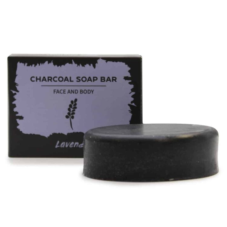 En mørkegrå sæbebar med en glat overflade og en let mat finish pryder midten. Baren har en rektangulær form med afrundede kanter. Der er indgraveret tekst, der angiver produktnavnet. Sæben udsender en svag lavendelduft, og dens overflade har små, fine bobler, der tilføjer en let tekstur.