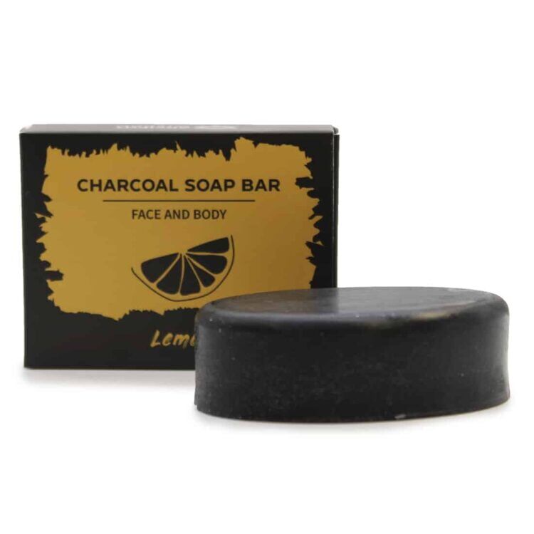 Sæbebaren præsenterer sig med en dyb, mørk grå farve, der minder om kul. Overfladen er glat med en let skinnende tekstur. En skarp, gul cirkel pryder den ene ende, sandsynligvis en citronskive, som tilføjer kontrast. Sæben har en rektangulær form med bløde kanter, og der kan ses små luftbobler i materialet, der giver en naturlig effekt.