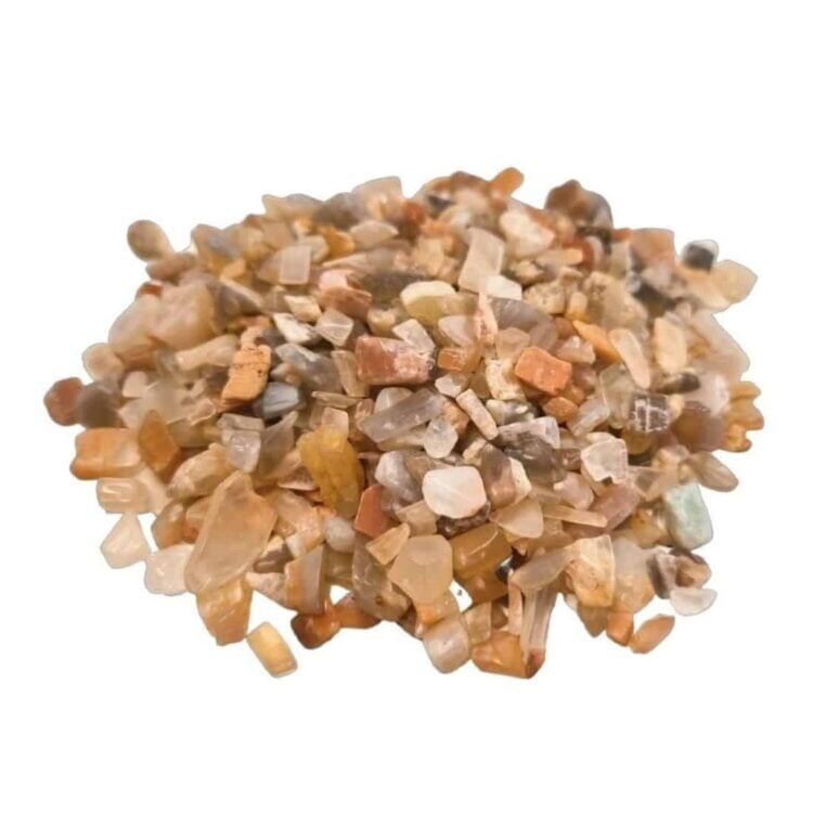 Små, uregelmæssige chips af månestene, der varierer i størrelse og form. De har en perlemorsagtig glans og en lys, næsten gennemsigtig kvalitet med nuancer af hvid, blå og grå. Overfladen er glat, og nogle chips har subtile striber og farveskift, der fremhæver deres naturlige skønhed. Chipsene er spredt jævnt på en neutral baggrund.