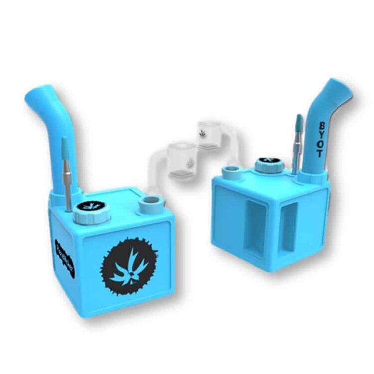 En kube i en dyb, mørkeblå farve pryder overfladen, med skarpe kanter og en ensartet struktur. Den har en mat finish, der giver den et moderne udtryk. På toppen sidder et lille, rundt håndtag i lys metal, der kontrasterer med den blå overflade. Kubeformen er simpel og funktionel, uden yderligere dekorationer.