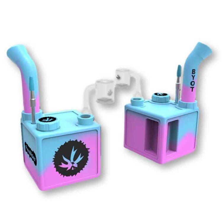 En kubeformet struktur præsenterer sig med en blød, pastelagtig lyserød farve. Overfladen har en mat tekstur, der giver et indtryk af stof. Kanten er let afrundet, og der er små detaljer, der skaber en struktur. Elementerne er symmetrisk placeret, hvilket giver en harmonisk og enkel komposition.