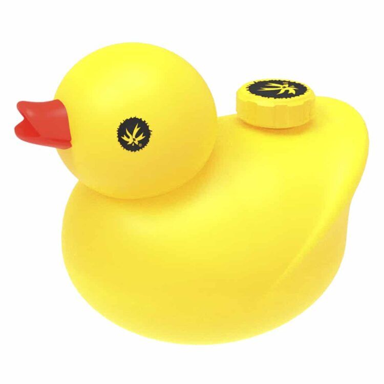 En gul, blød figur med en rund form og en flad bund pryder overfladen. Figuren har en stor, oval næbformet del foran, der strækker sig ud fra en krop, der er let buet. Overfladen er ensartet og glat med en mat finish, mens øjnene er små og runde, placeret tæt på næbbet. Farven er intens og ensartet.