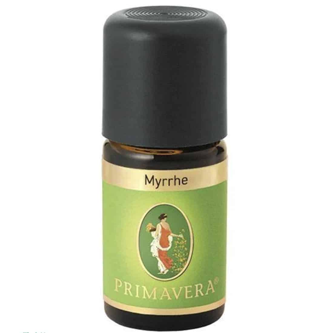 En lille, klar glasflaske indeholder en gylden væske. Flasken har en rund, slank form og en mørk, elegant låg. Et label i lyse nuancer pryder flaskens front med tekst og grafiske elementer, der angiver produktets navn og indhold. Flaskens overflade har en glat, skinnende finish, der reflekterer lyset.