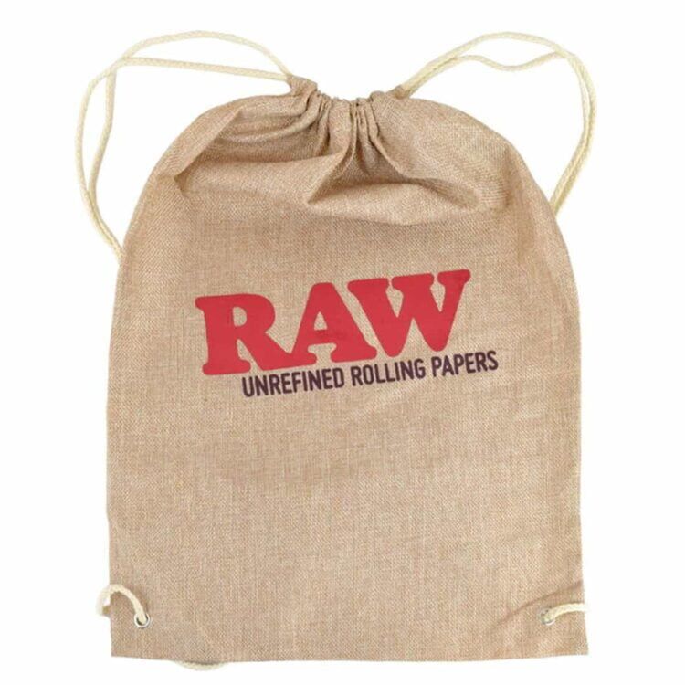 En taske i en lys tan farve med en glat overflade og en blød tekstur. Tasken har en simpel, cylindrisk form og er lukket med en snøre, der er trukket gennem et par huller i toppen. Snøren er i en matchende farve, mens taskens inderside er ensartet og kan ses gennem åbningen. Tasken har ingen yderligere mønstre eller dekorationer.