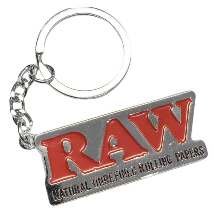 Nøgleringen er lavet af rå metal med en ru, ubehandlet overflade, der giver et industrielt udtryk. Den har en cirkulær form og en solid, tyk struktur. Et lille, åbent spænde holder nøglerne på plads. Farven er en mørk sølvgrå, og der er synlige tegn på slid, hvilket tilføjer karakter til objektet.