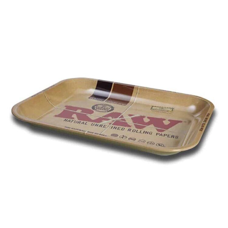 Et rektangulært rullebræt i rå metal præsenterer en mat, grå overflade med lette strukturer og ujævnheder, der skaber en industriel æstetik. Kanterne er let opadvendte, hvilket giver en praktisk form. I midten er der et indgraveret mønster, der tilføjer en subtil detalje. Brættets overflade reflekterer svagt lys, hvilket skaber en blød glans.