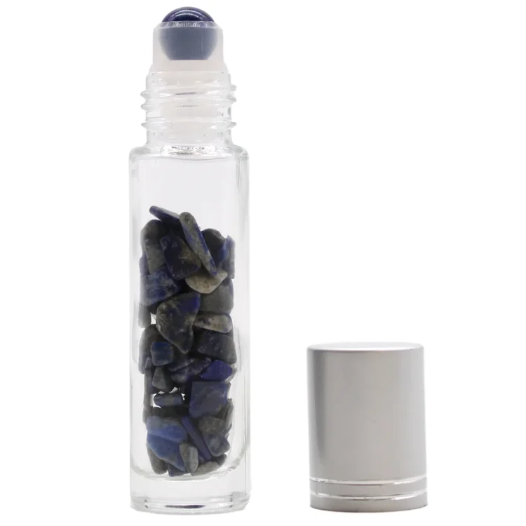 En mørkeblå rollerflaske er præsenteret med en glat, blank overflade, der reflekterer lys. Flaskens form er slank og cylindrisk med en rund bund og en smal åbning. Korken er lavet af metal og har en lille kugle, der fungerer som roller. Flasken har en tydelig struktur med nuancer af blå og grå, som giver et naturligt udtryk.