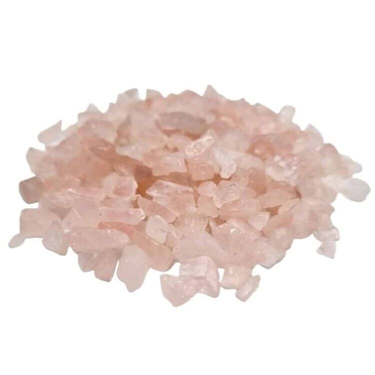 Rosenkvarts chips præsenterer en lyserød farvetone med varierende nuancer fra sart pastelmørk til dybere rosa. De små, ujævne sten har en glat overflade og et let transparent udseende. Nogle chips har naturlige sprækker og uregelmæssigheder, hvilket giver et organisk præg. Stenene ligger spredt, hvilket fremhæver deres forskellige former og størrelser.