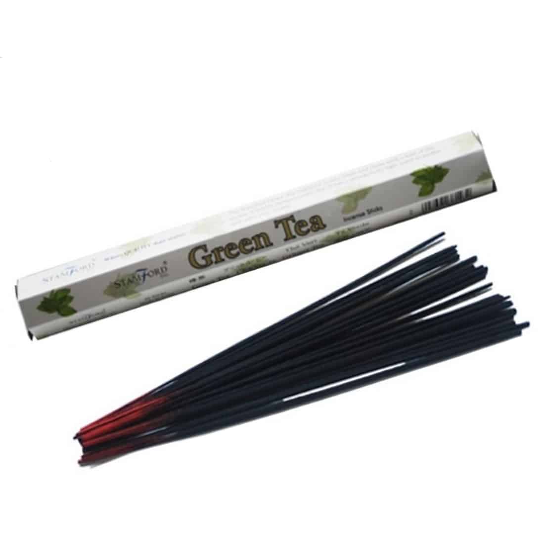 Pakke med 20 tebreve præsenteret i en rektangulær, grøn boks. Boksens overflade er glat med en mat finish, prydet med hvid tekst og et enkelt, stiliseret logo i guld. Indholdet, tebrevene, er individuelt pakket i papir med grønne og hvide nuancer. Hver tepose er lukket med en snor og har et lille label med tekst.