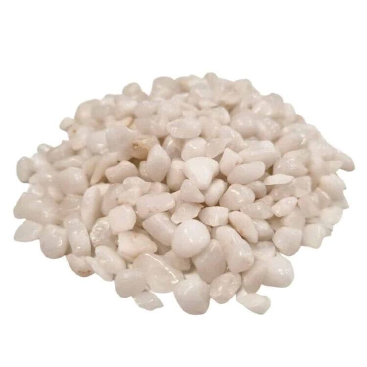 Hvide kvartsædelsten chips præsenteres i en lille klar plastpose. Chipsene varierer i størrelse og form, med glatte, polerede overflader, der reflekterer lys. Farven spænder fra næsten gennemsigtig til en blød hvid nuance. Posens etikette indeholder tekst og symboler, der angiver produktets vægt på 20 gram. Baggrunden er neutral og understøtter fokus på ædelstenene.