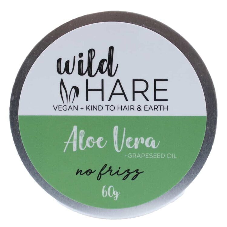 Et rundt, kompakt stykke shampoo med en glat, ensartet overflade i en lys grøn nuance. Den har en let skinnende tekstur, der indikerer fugtighed. Øverst er der en delikat præget tekst med produktnavnet, mens siderne er glatte uden synlige knapper eller symboler. Materialet fremstår solidt og fast, velegnet til opbevaring.