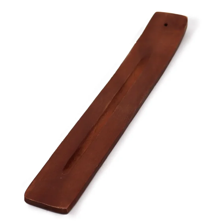 En røgelsespindeholder i mango-træ præsenterer en naturlig, varm brun farve med fine, gyldne nuancer. Den har en rektangulær form med afrundede kanter, hvilket skaber et blødt udtryk. Overfladen har en let struktureret tekstur, der fremhæver træets årer og naturlige mønstre. Der er en smal fordybning til at holde røgelsespinde stabilt.