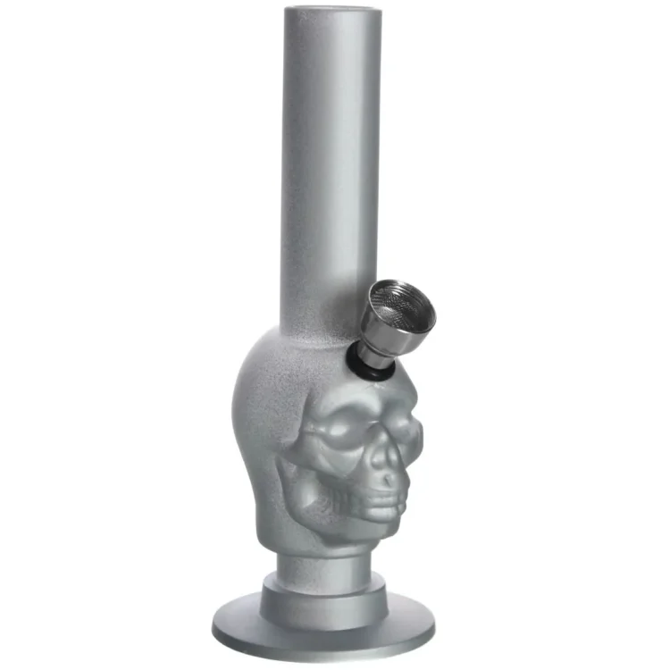 En sølvfarvet bong i form af et kranium, fremstillet af gummi. Den har en glat overflade med en let mat tekstur. Øjnene og næsen på kraniet er tydeligt udskåret, hvilket giver det et dramatisk udseende. Bongen har en traditionel form med en afbøjning i halsen og en skål til tobak, placeret på toppen af kraniet.