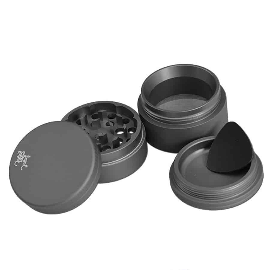 En sort kværn med en mat grå overflade pryder midten af beskrivelsen. Kværnen har en rund form med en diameter på 49 mm. Den er fremstillet af metal og har en tekstureret overflade, der giver et moderne udtryk. Kværnen er udstyret med små, skarpe tænder indeni samt en drejeanordning, der muliggør nem brug.