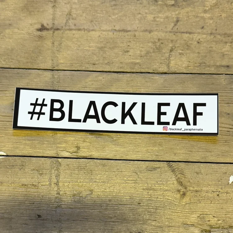 Et klistermærke med en stiliseret sort bladform, der pryder en hvid baggrund. Bladet har en glat overflade med detaljerede åretegninger, der skaber kontrast til den ensfarvede baggrund. Kanterne af klistermærket er skarpe, og det fremstår som en enkel, men elegant dekoration, der tilføjer et naturligt element til en flade.