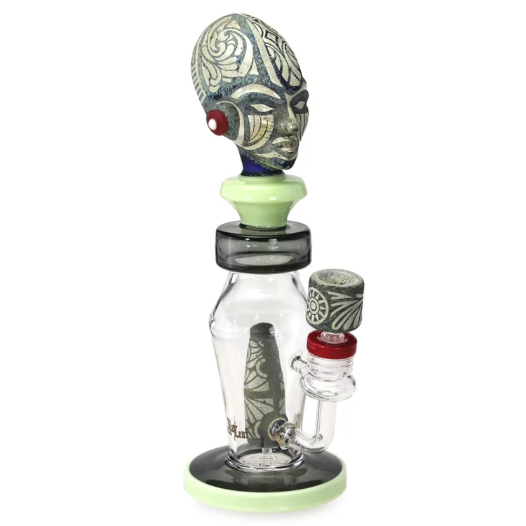 En høj diffusorbong i sort glas, præget af en elegant, glat overflade. Den er 31 cm høj med en bred, stabil fod og en slank hals, der leder op til en åbning. Bongen har en detaljeret, bladformet dekoration, der tilføjer et organisk element. Den har en indbygget diffuser med flere små huller, der sikrer optimal filtrering.