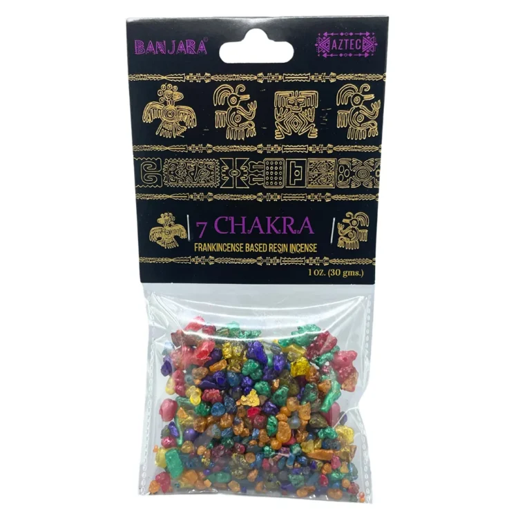 En rund skive i naturlig harpiks prydes af syv farverige chakra-symboler, der er indgraveret i overfladen. Farverne spænder fra rød, orange, gul, grøn, blå, indigo til violet, hver med en glat og skinnende finish. Baggrunden er gennemsigtig og let flettet med subtile nuancer af brun og grøn, hvilket fremhæver de farverige symboler.