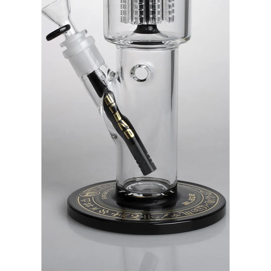 En høj, gennemskinnelig bong i klart glas pryder centralt med en slank, cylindrisk form. Den er udstyret med en kompleks, 10-armet perkolator, der skaber et intrikat netværk af rør og kanaler. Overfladen er glat med en subtil glans, og toppen afsluttes med en bred, åbning. Farverne er dominerende klare, med enkelte detaljer, der fremhæver designets elegance.