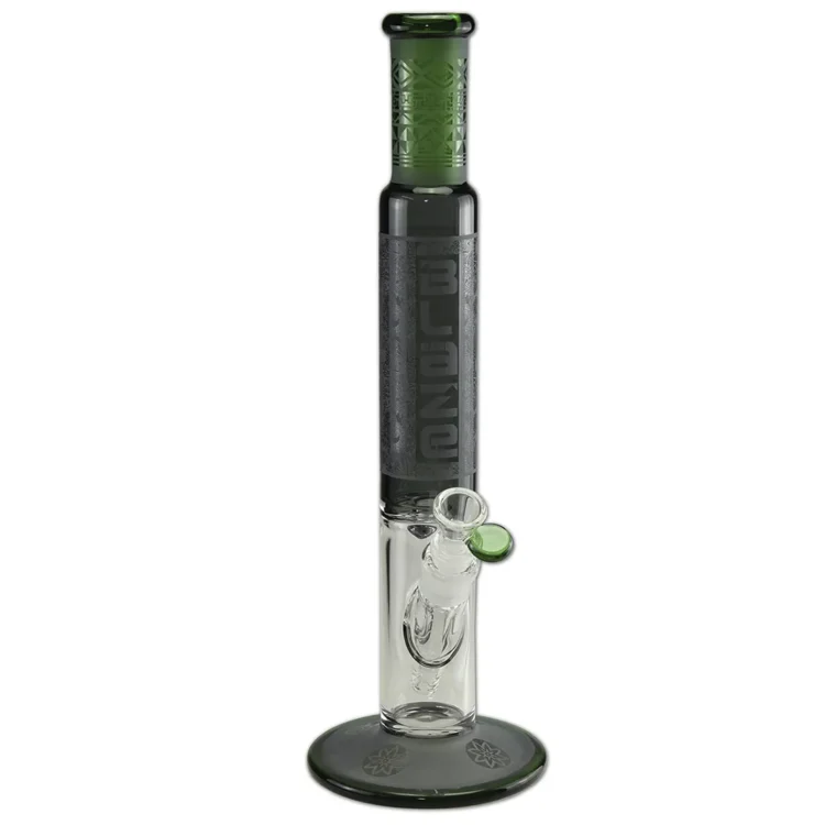 En grøn glasvase med en cylinderformet silhuet. Overfladen er glat med en let gennemsigtig effekt, der fremhæver den dybe, ensartede farve. Vasen har en bred åbning foroven og en slankere base. Teksturen er ensartet uden mønstre, hvilket giver et moderne og minimalistisk udtryk. Den står stabilt på en flad overflade.