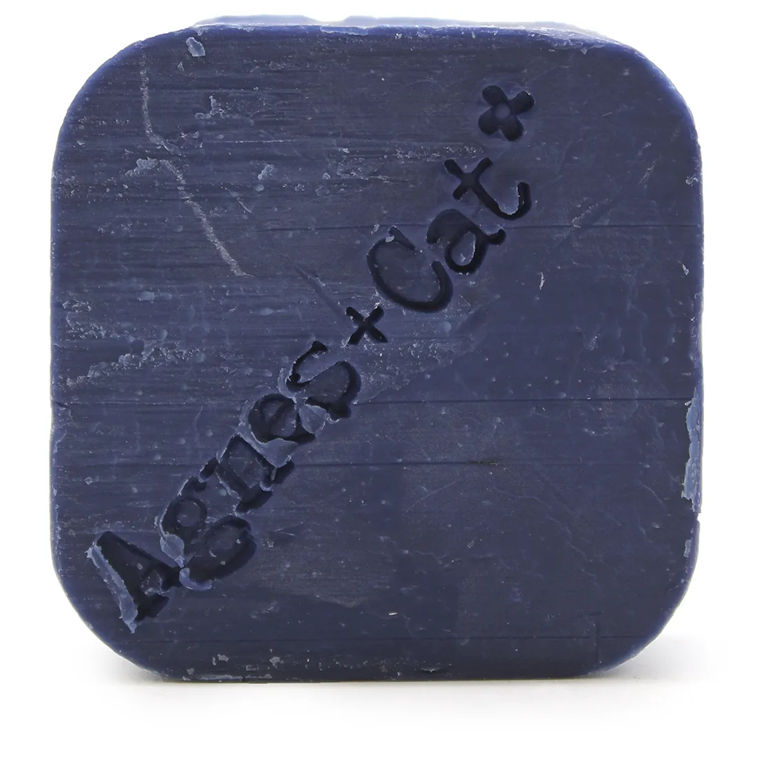 En solid shampoo-bar præsenterer sig med en rund form, der har en let skrånende kant. Overfladen er glat og skinnende, med en lys, pastelfarvet nuance, der minder om lys lavendel. Produktet er indgraveret med små detaljer, der skaber et diskret mønster. Ingen synlige emballager eller etiketter er til stede, hvilket giver et minimalistisk udtryk.