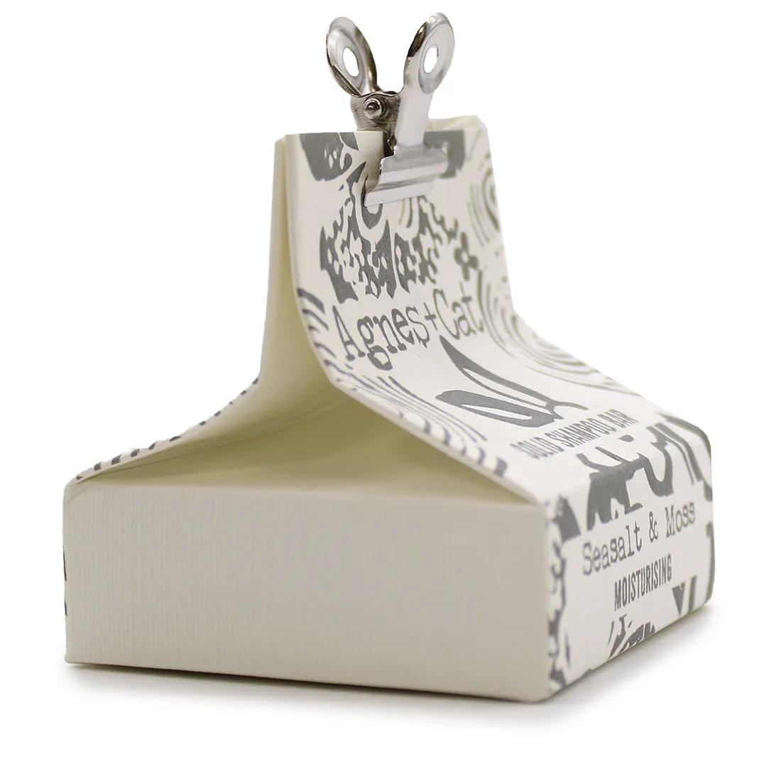 En solid shampoo bar præsenterer sig i en rund form med en glat overflade. Farven er en dyb, mættet grøn nuanceret med subtile striber i lysere toner. Teksturen er blød med en let skinnende finish. En indgraveret logo og tekst på overfladen tilføjer detaljer. Baren er placeret på en neutral baggrund, hvilket fremhæver dens naturlige skønhed.