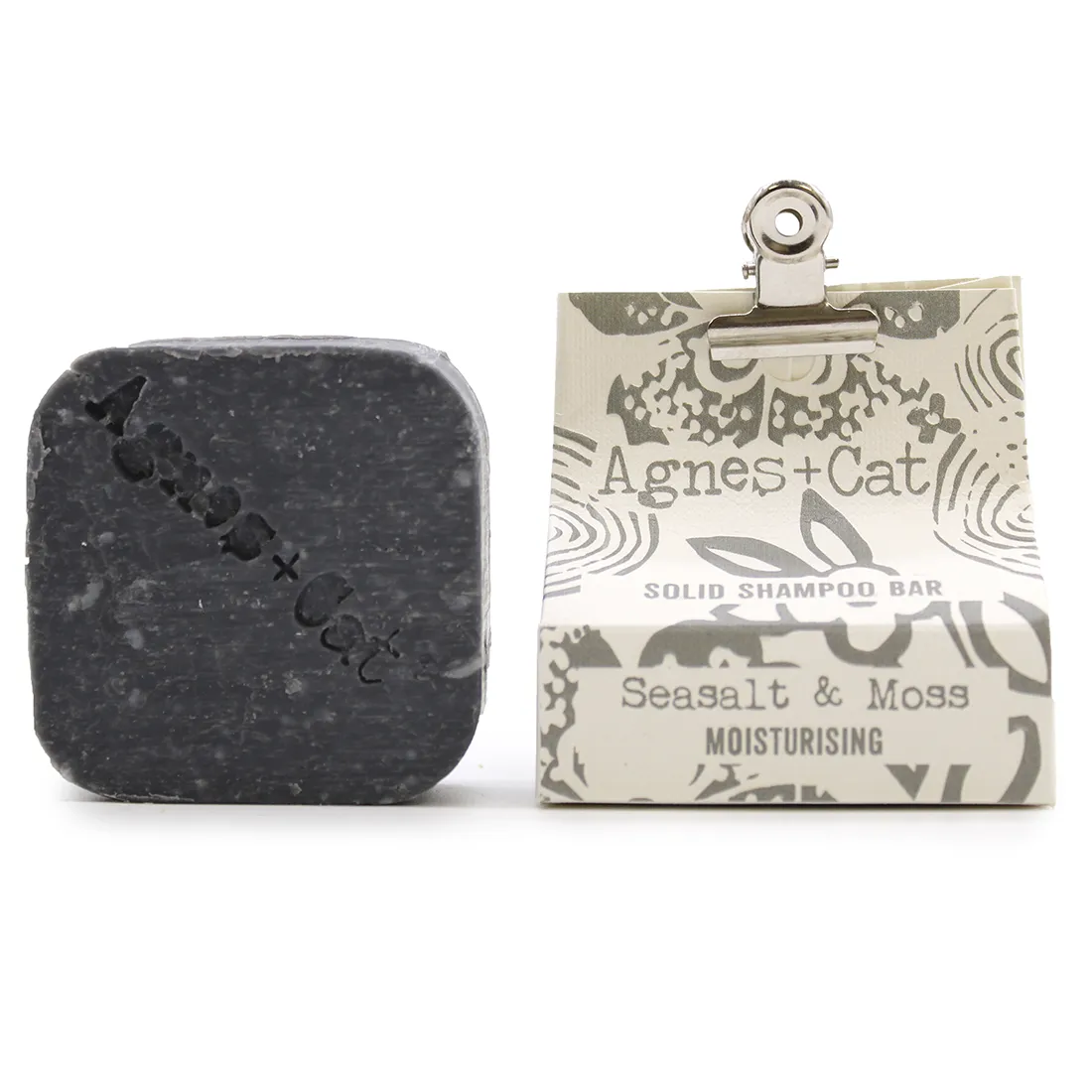 En solid shampoo bar præsenteres i en rund, flad form med en let bølget overflade. Farven er en blød grøn nuanceret i havsalat og mos, hvilket giver en naturlig og organisk følelse. Overfladen har en mat tekstur, og der ses små, uregelmæssige mønstre, der tilføjer dybde og karakter. Den er placeret på en lys, neutral baggrund.