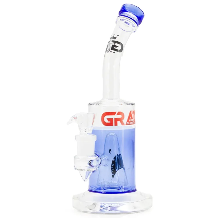 En 28 cm høj bong i klart glas med en slank, cylindrisk form. Den øverste del har en bred åbning, mens bunden er udstyret med et afrundet fodområde for stabilitet. Mønsteret af bølger og hajer i nuancer af blå og hvid pryder glasset, hvilket skaber en dynamisk effekt. En metal skål er fastgjort til røret, der strækker sig ned i vandkammeret.