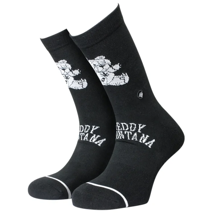 Crew-sokkerne er fremstillet af en blød, teddy-lignende tekstil med en varm, brun farve, der minder om en varm chokolade. Sokkerne har en ribbet struktur ved anklen, hvilket giver dem en elastisk pasform. Sømmene er ensartede, og der er ingen synlige logoer eller mærker. Sålen er flad og ensfarvet, hvilket giver et minimalistisk udtryk.