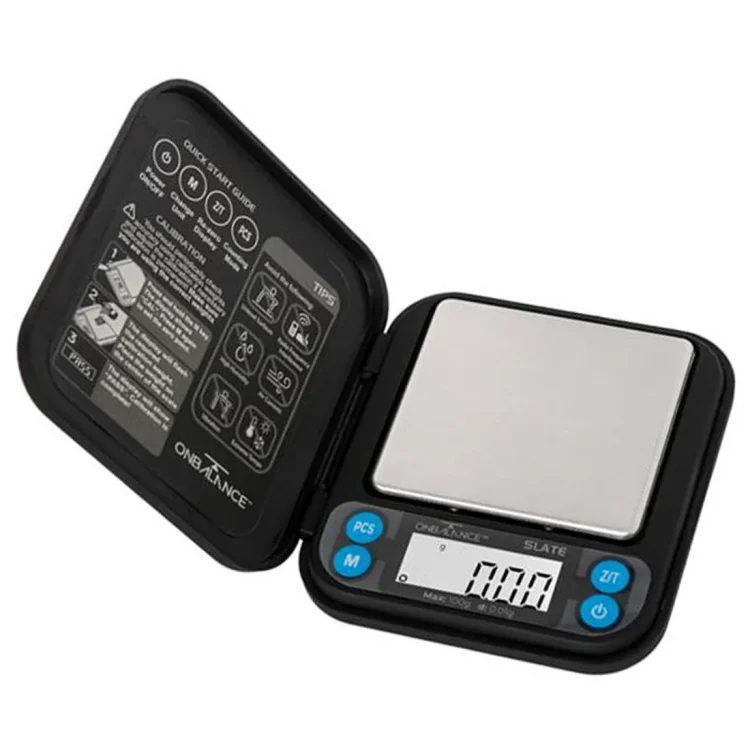 En vægt med en rund, flad plade i sølvfarvet metal, der har en glat, reflekterende overflade. Vægten har en digital skærm, der viser tal i klart, sort skrift. Knapperne er placeret under skærmen, i sort plast med hvide symboler. Base af vægten er stabil og firkantet, med skridsikre gummifødder for bedre greb.